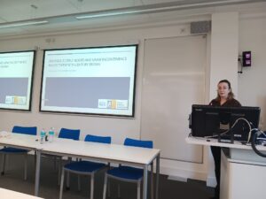 Image shows Kate McAllister facing the camera, presenting in front of a whiteboard.