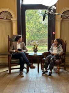 Two people sitting in chairs, facing one another.