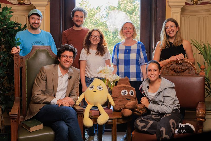 A group of people stand and sit facing the camera.