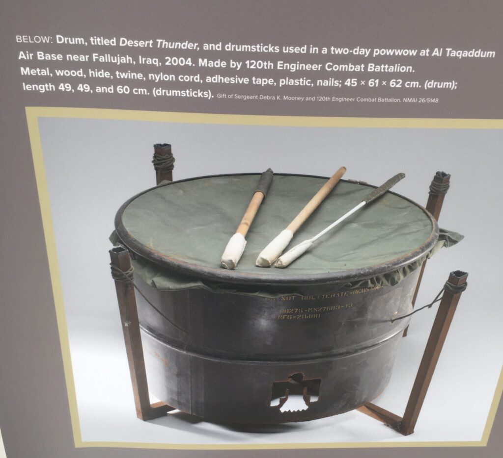 Photograph of a museum panel depicting a large drum that was used in a two day powwow near Fallujah, Iraq in 2004.