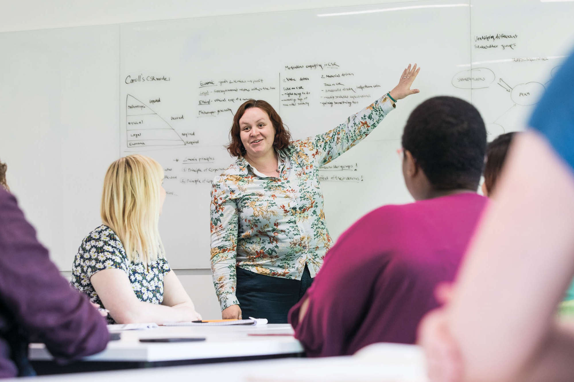 Instructor pointing to white board with students looking