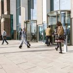 Peopling entering and exiting a building through two revolving doors