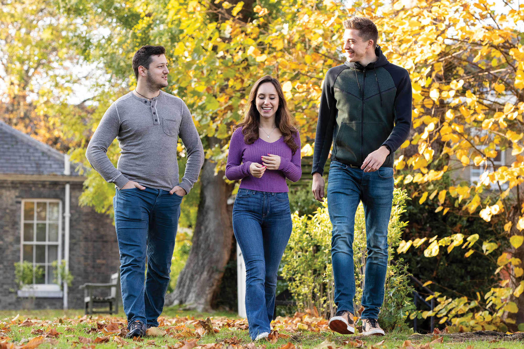 Three people walking forwards in a garden