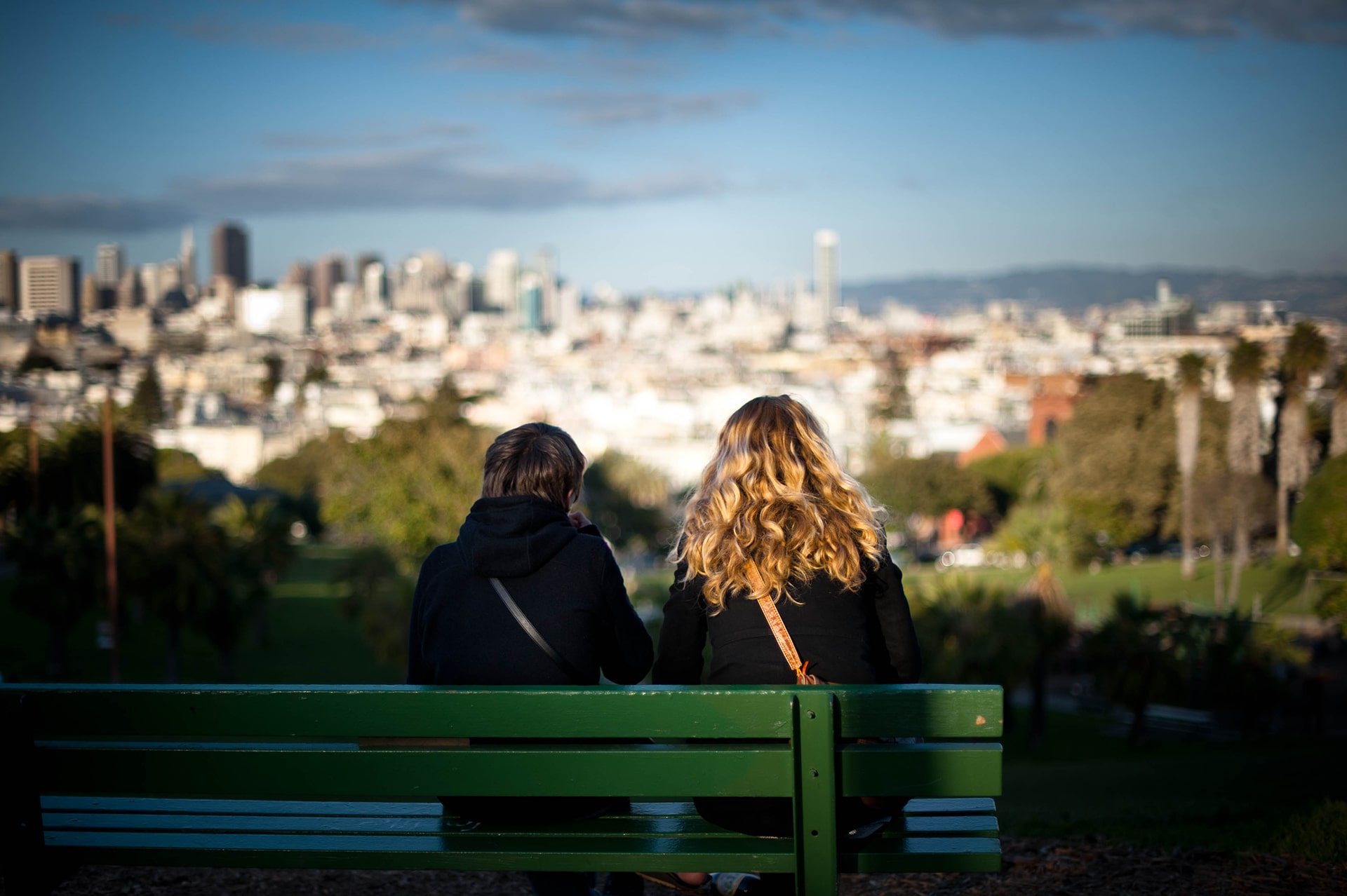 Two people sitting on the bench enjoying a sunset view from the top of Dolores Park in San Francisco