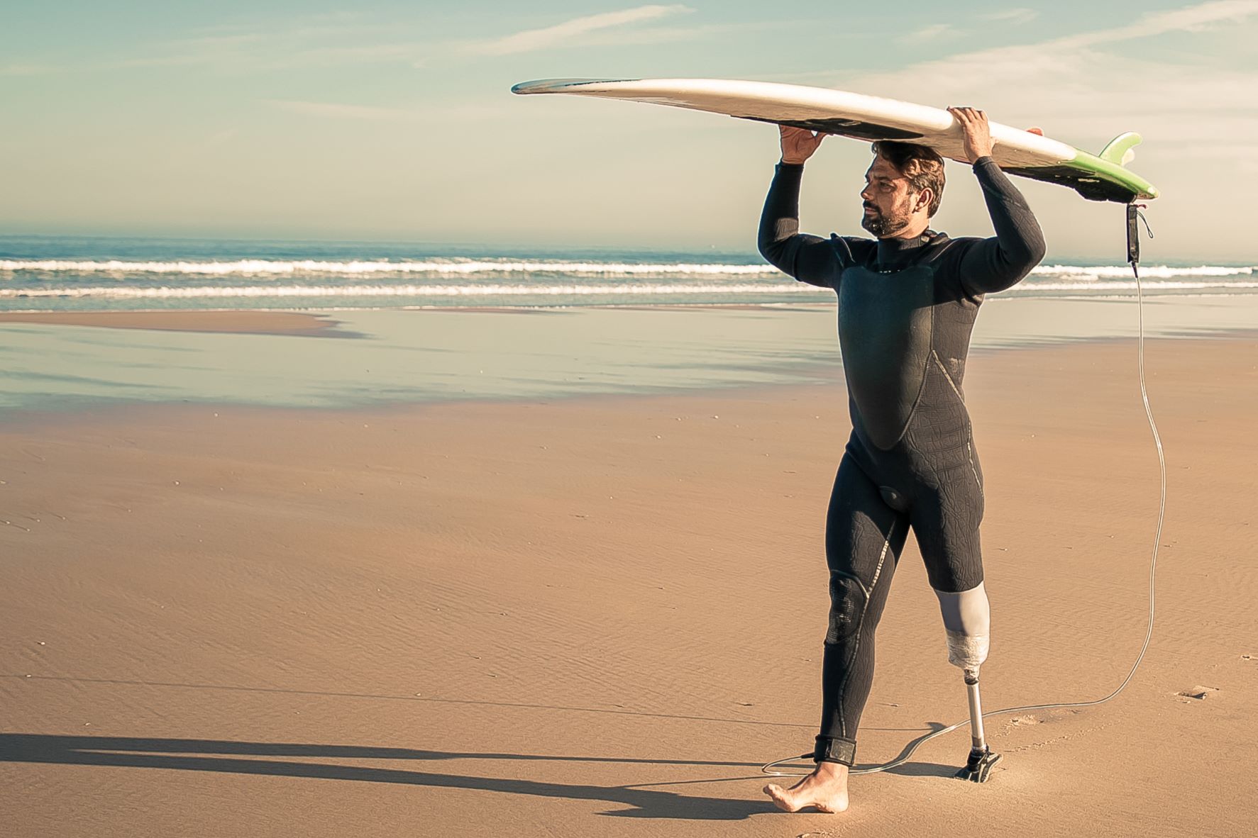 Surfer walking along a beach, surfboard held above head